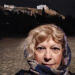 Απεικονίζεται η συγγραφέας Μαρία Μπούκλα μπροστά από τον βράχο της Ακρόπολης